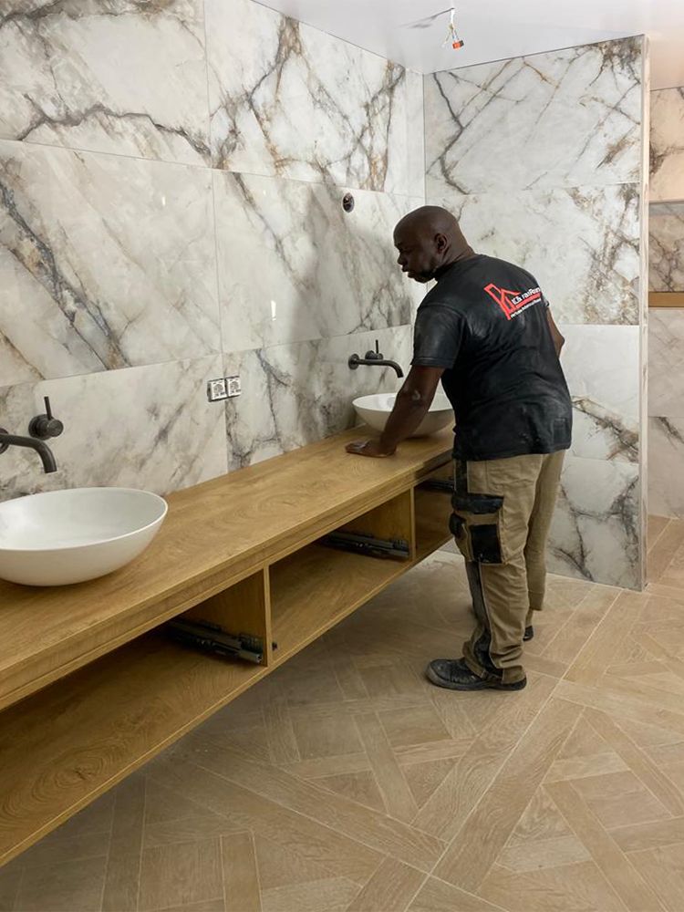 Een man staat naast een wastafel in een badkamer.