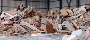 Piled demolition debris and broken wood inside an industrial warehouse