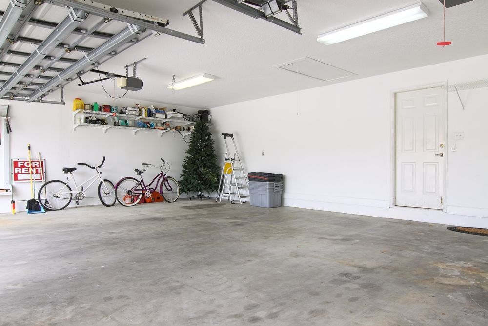 Empty garage with concrete floor, bikes lined along the wall, and a white door on the right