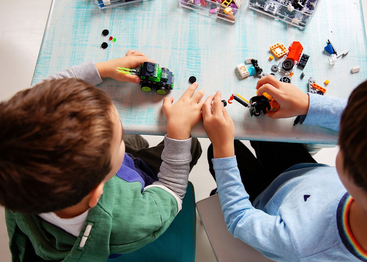 Group of smiling children lying in a circle and looking down at the camera, wearing colorful shirts