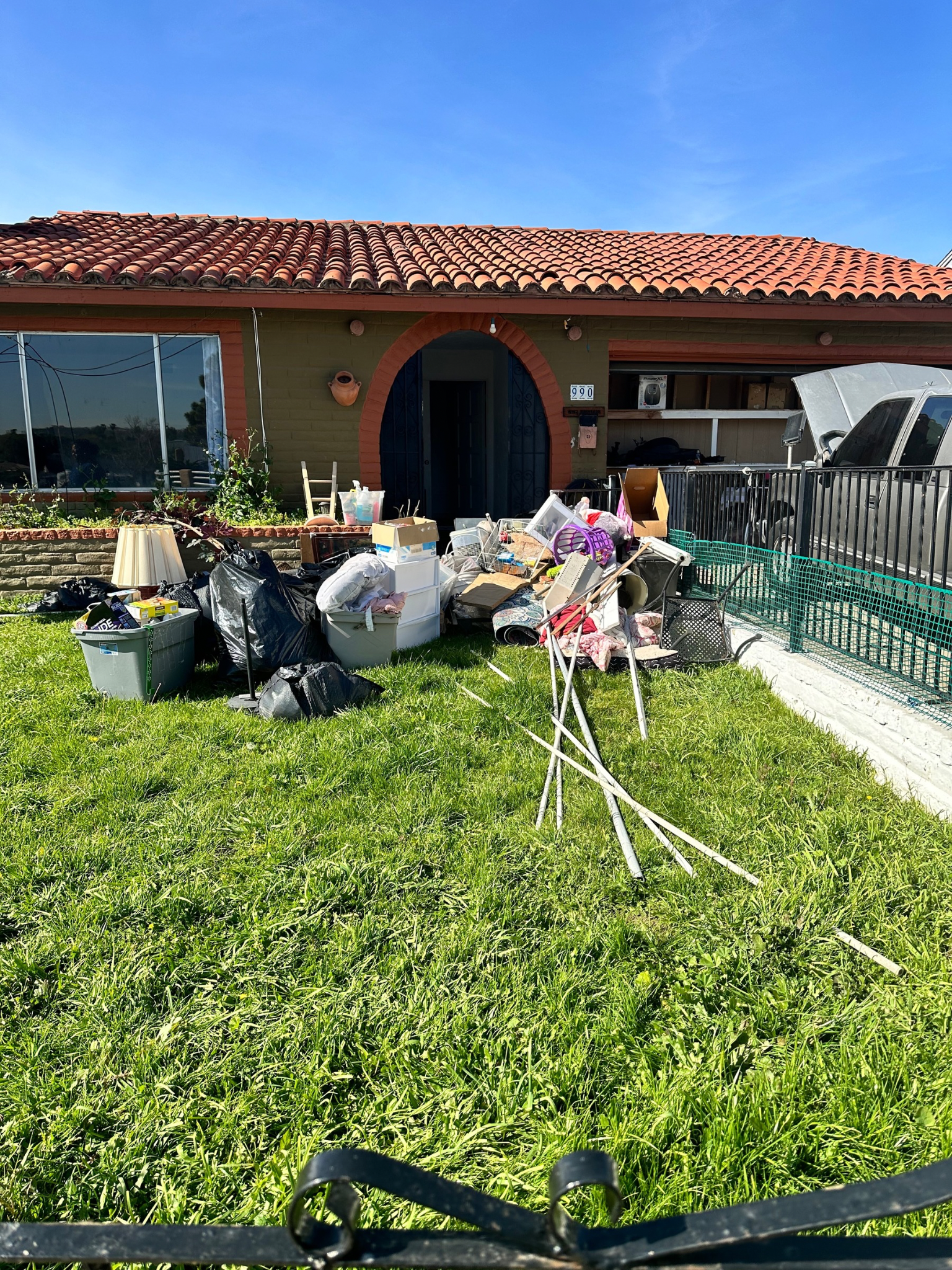 A house with a lot of trash and junk ready to be picked up.