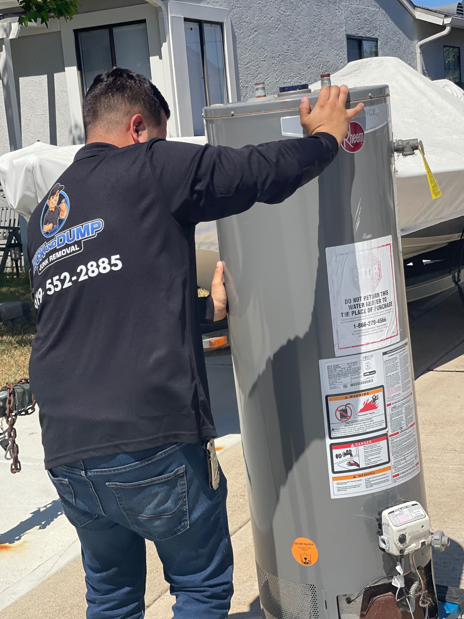 A man in a black shirt is removing a water heater.