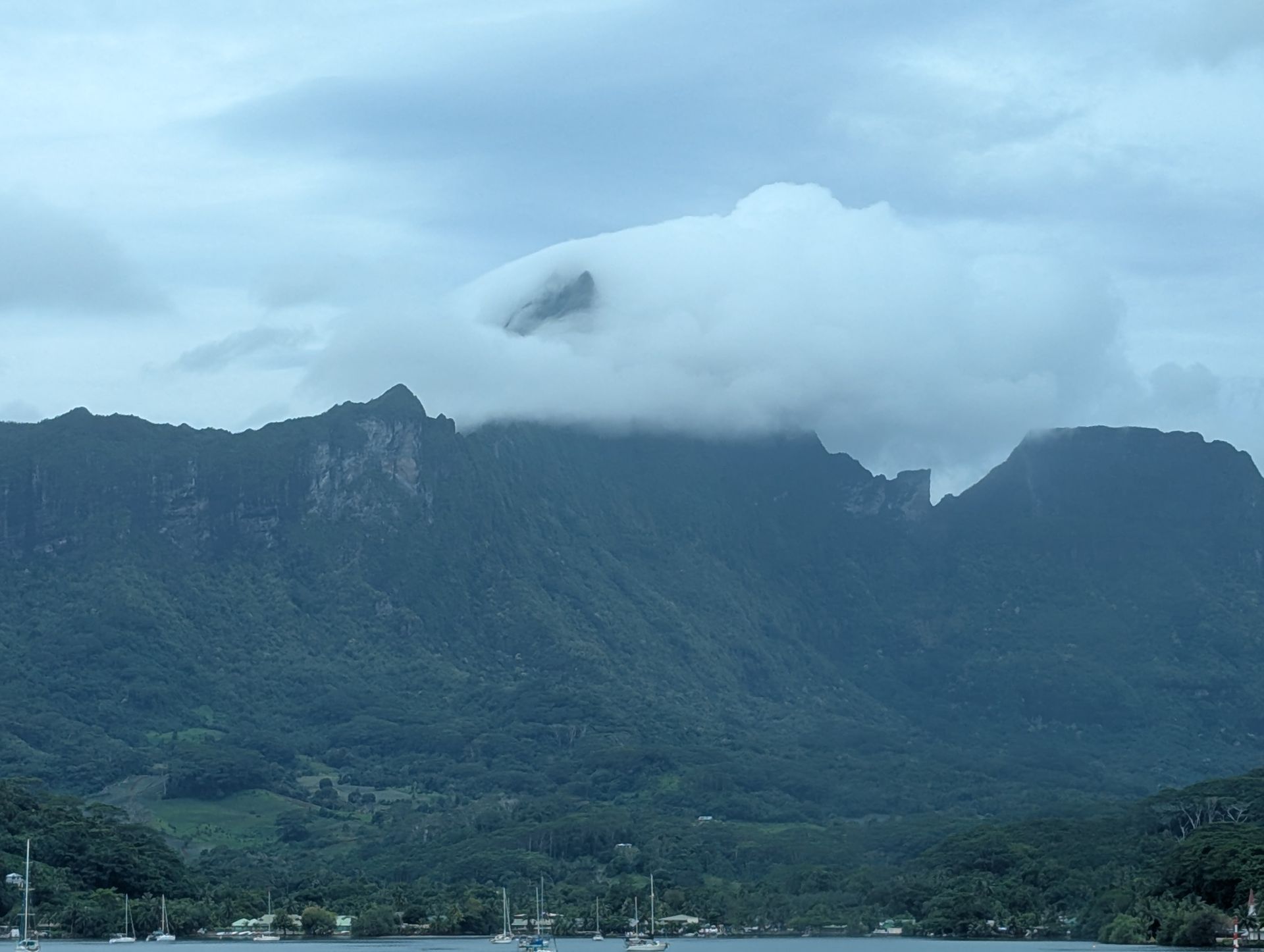 Two kayaks on a calm lake, with mountains and cloudy sky in the background.
