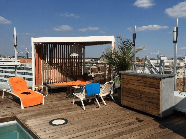 A rooftop deck with a swimming pool and chairs