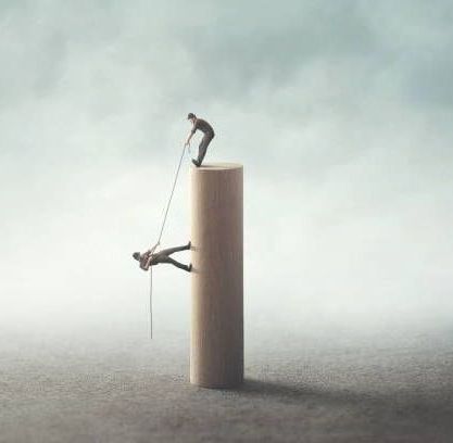 A man is climbing a wooden pillar with a rope.