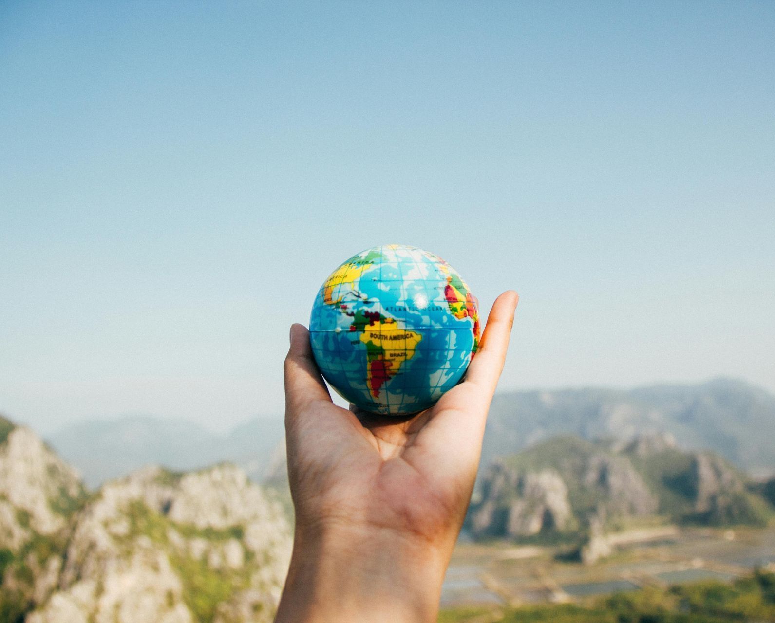 A person is holding a small globe in their hand.