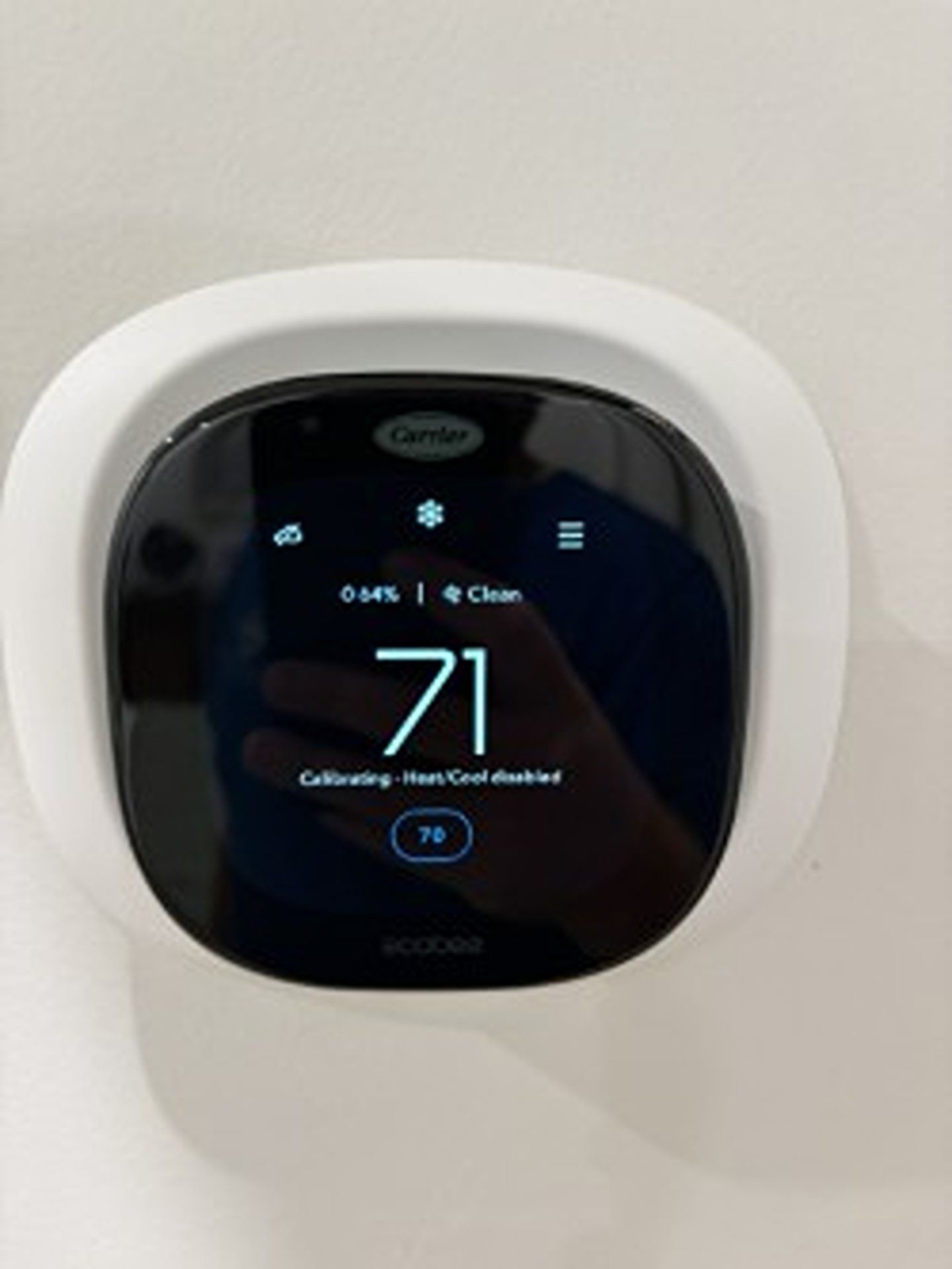 White Carrier smart thermostat displaying 71°F on a wall.