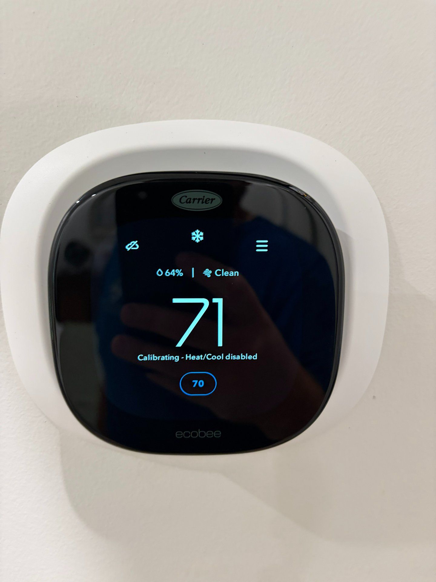 Round black smart thermostat on a white wall displaying 71°F.