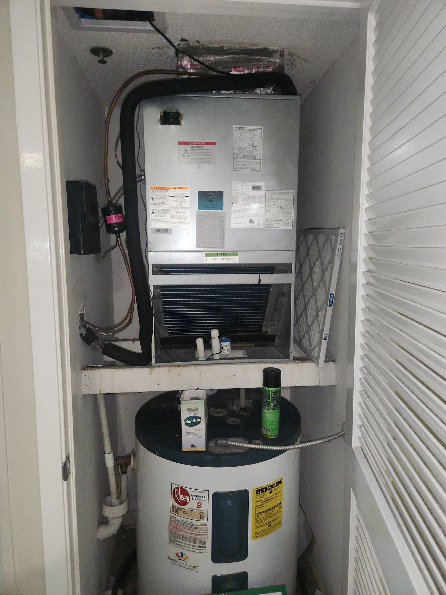 Utility closet with a wall-mounted HVAC unit above a white water heater and cleaning supplies below