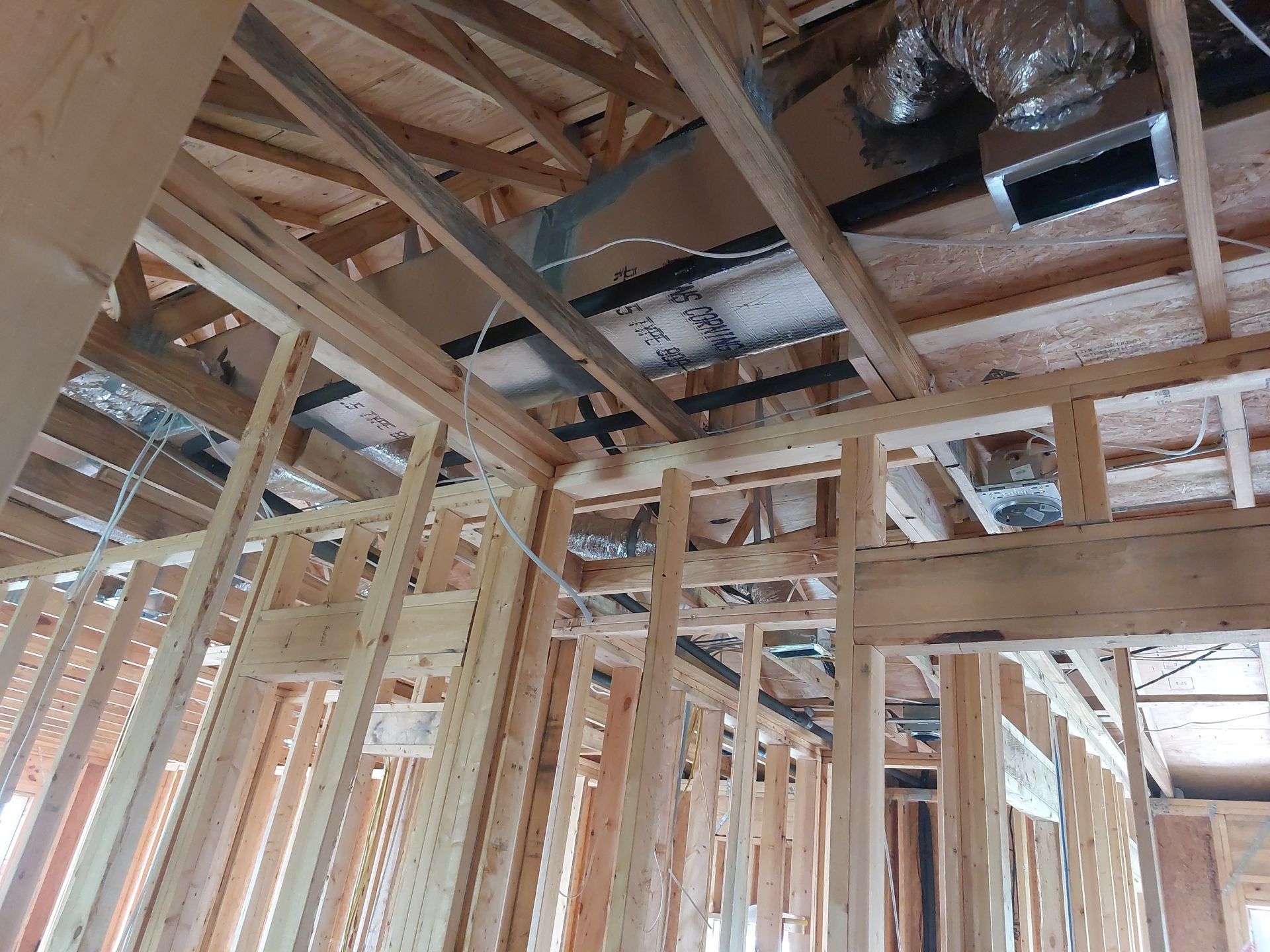 Interior of a house under construction with exposed wooden framing and roof trusses