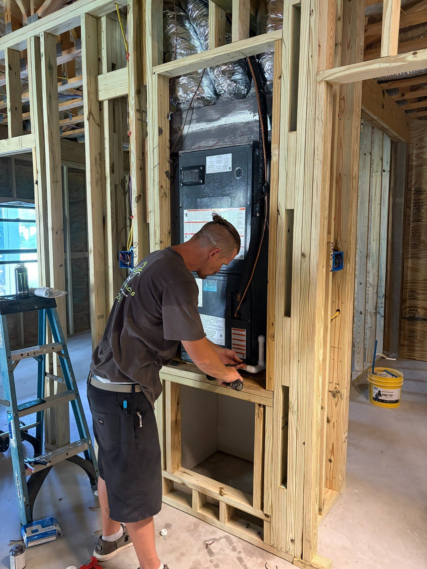 Worker installing a window in an unfinished wooden wall inside a framed house