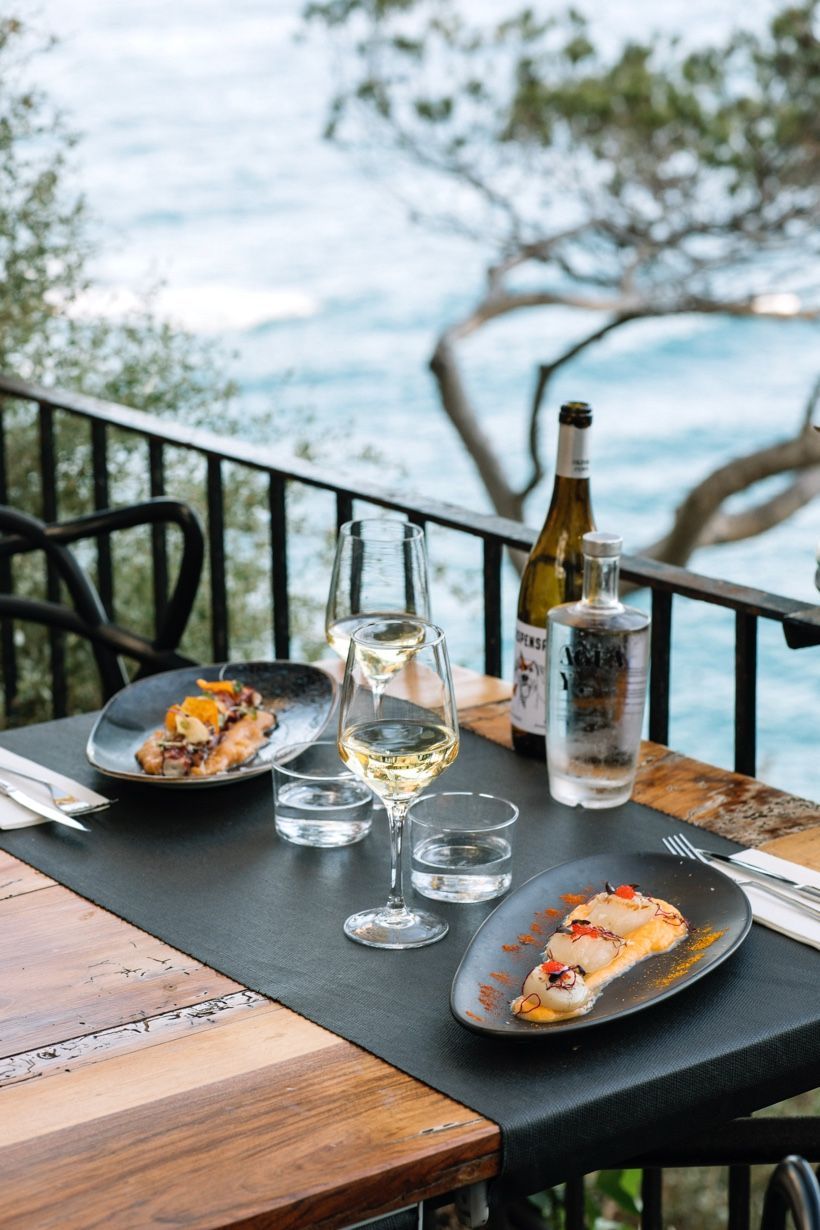 A table with plates of food , glasses of wine and a bottle of wine.