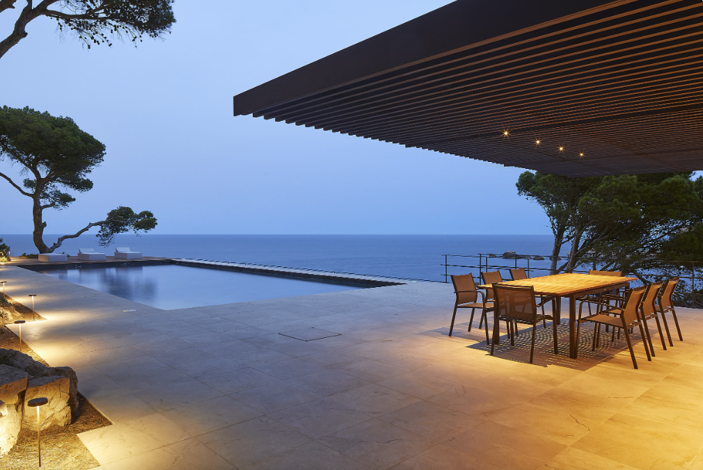 A patio with a table and chairs overlooking the ocean