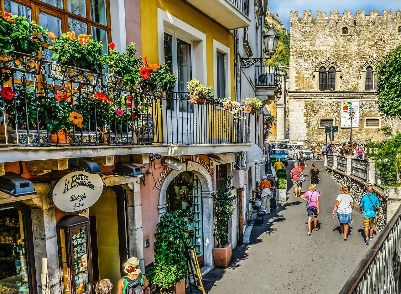 A group of people are walking down a narrow street in a city.
