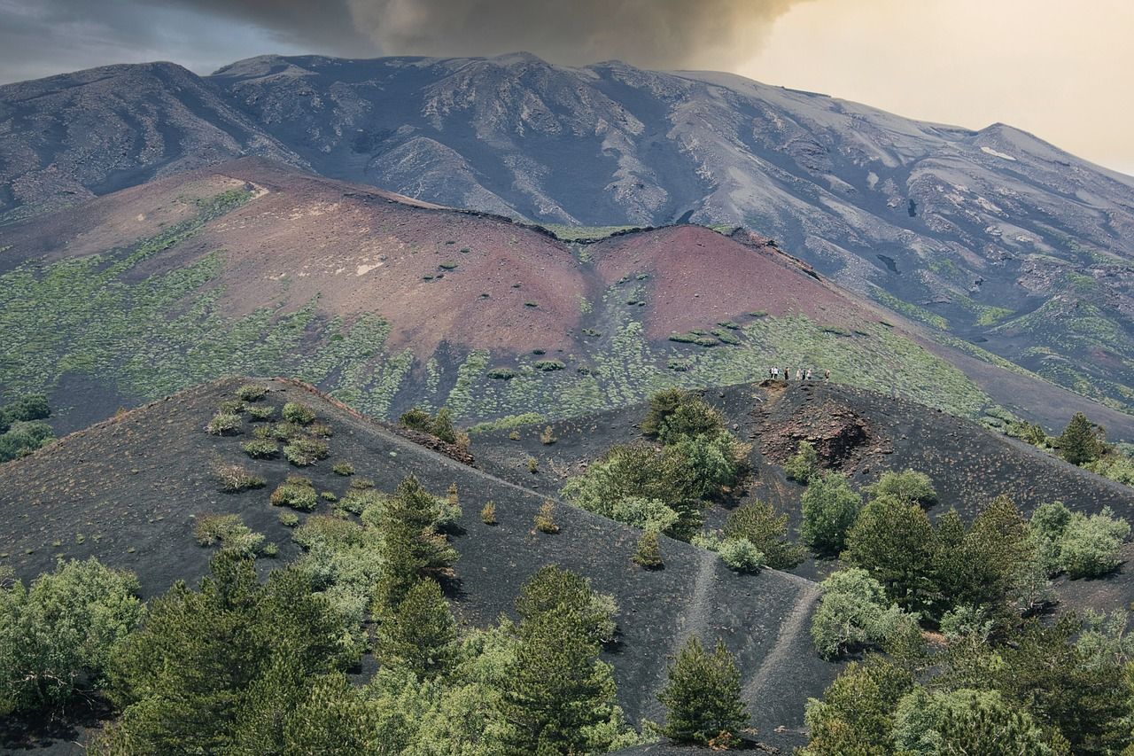 A mountain covered in trees with a cloudy sky in the background.