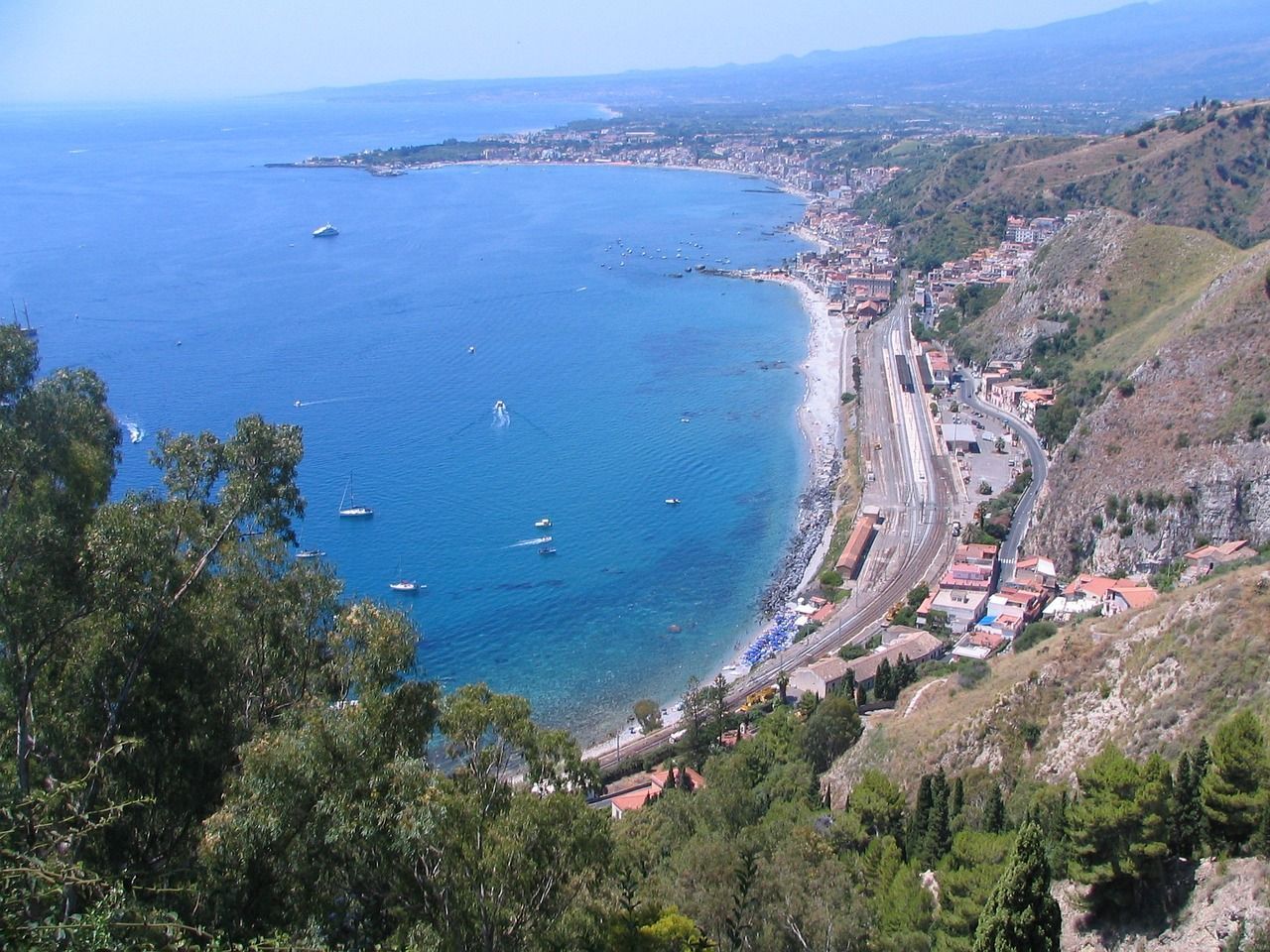 An aerial view of a beach with boats in the water