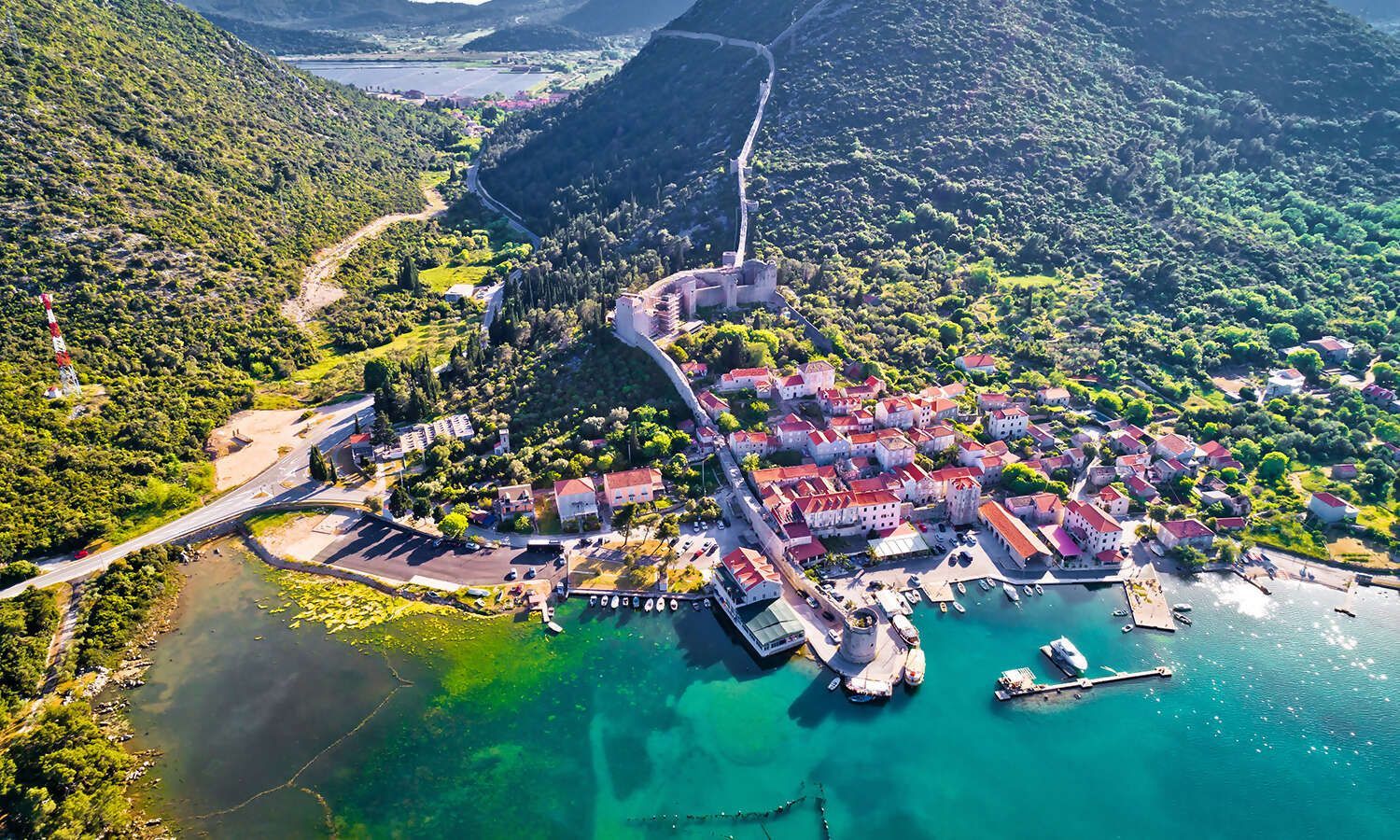 An aerial view of a small town in the middle of a lake surrounded by mountains.