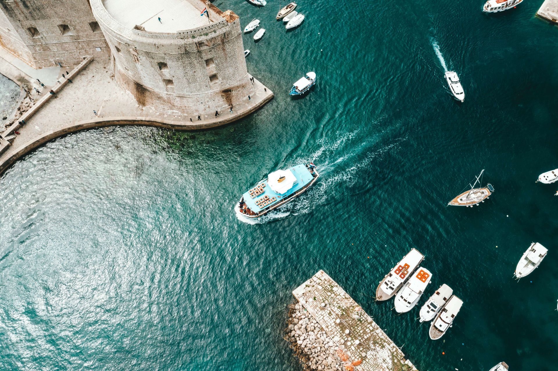 An aerial view of a harbor with boats and a castle in the background.