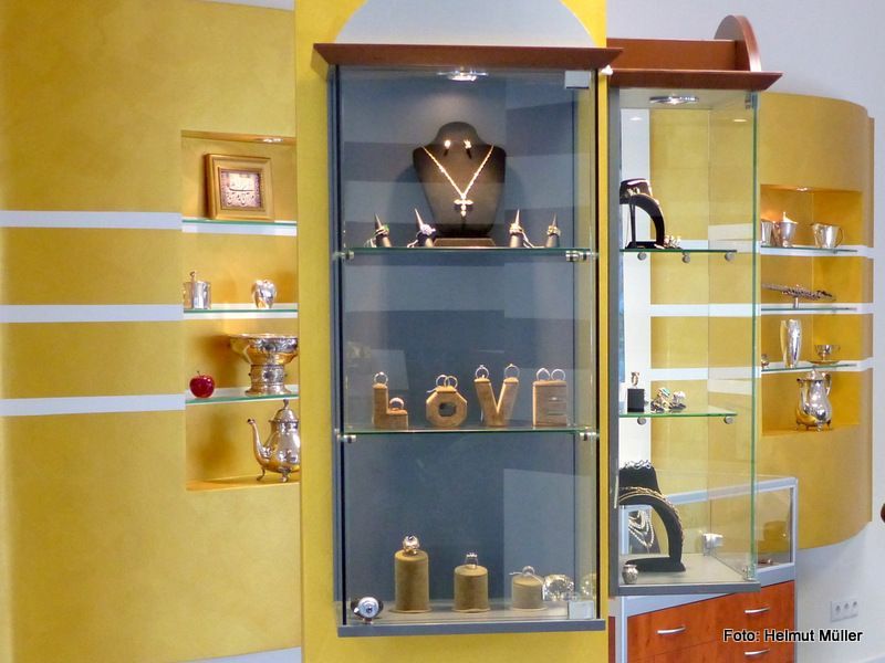 Schmuckvitrine mit goldenen und blauen Regalböden, auf der Halsketten, Ringe und das Wort „LOVE“ in der Mitte ausgestellt sind.