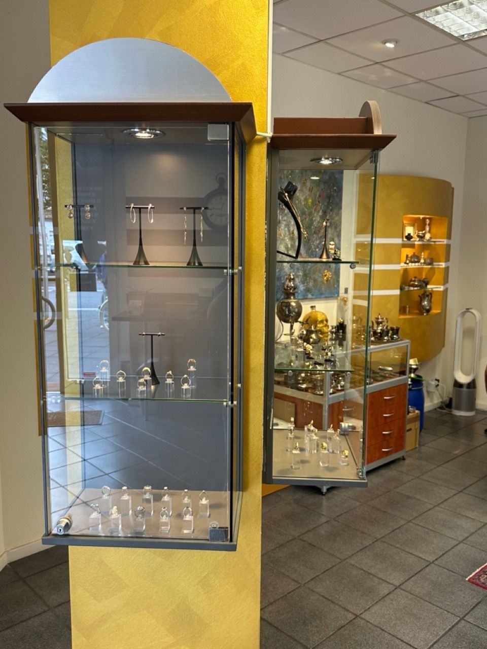 Glasvitrinen mit Glaswaren und Dekorationsartikeln in einem gefliesten Ladenlokal oder einer Galerie.