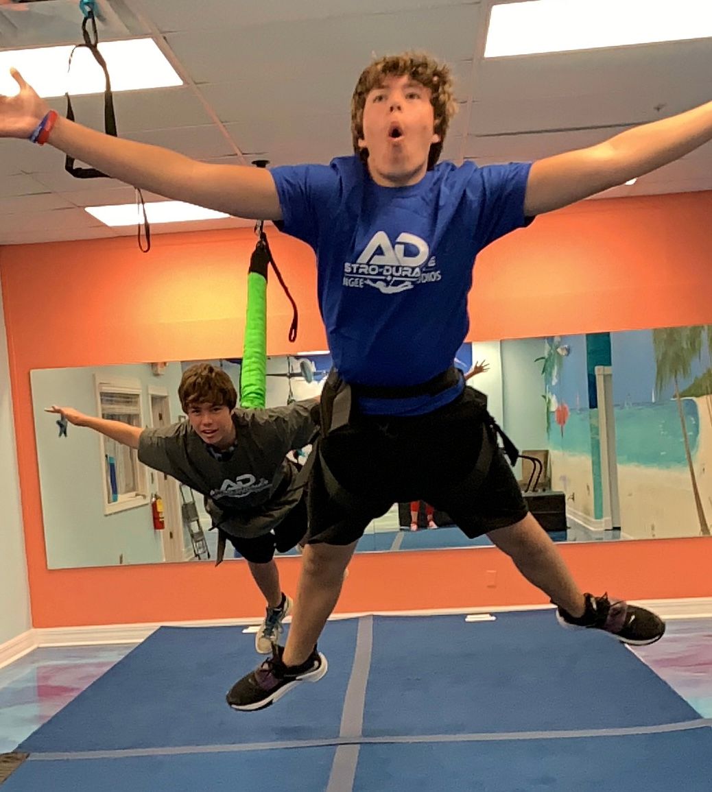 A boy in a blue ad shirt is jumping in the air