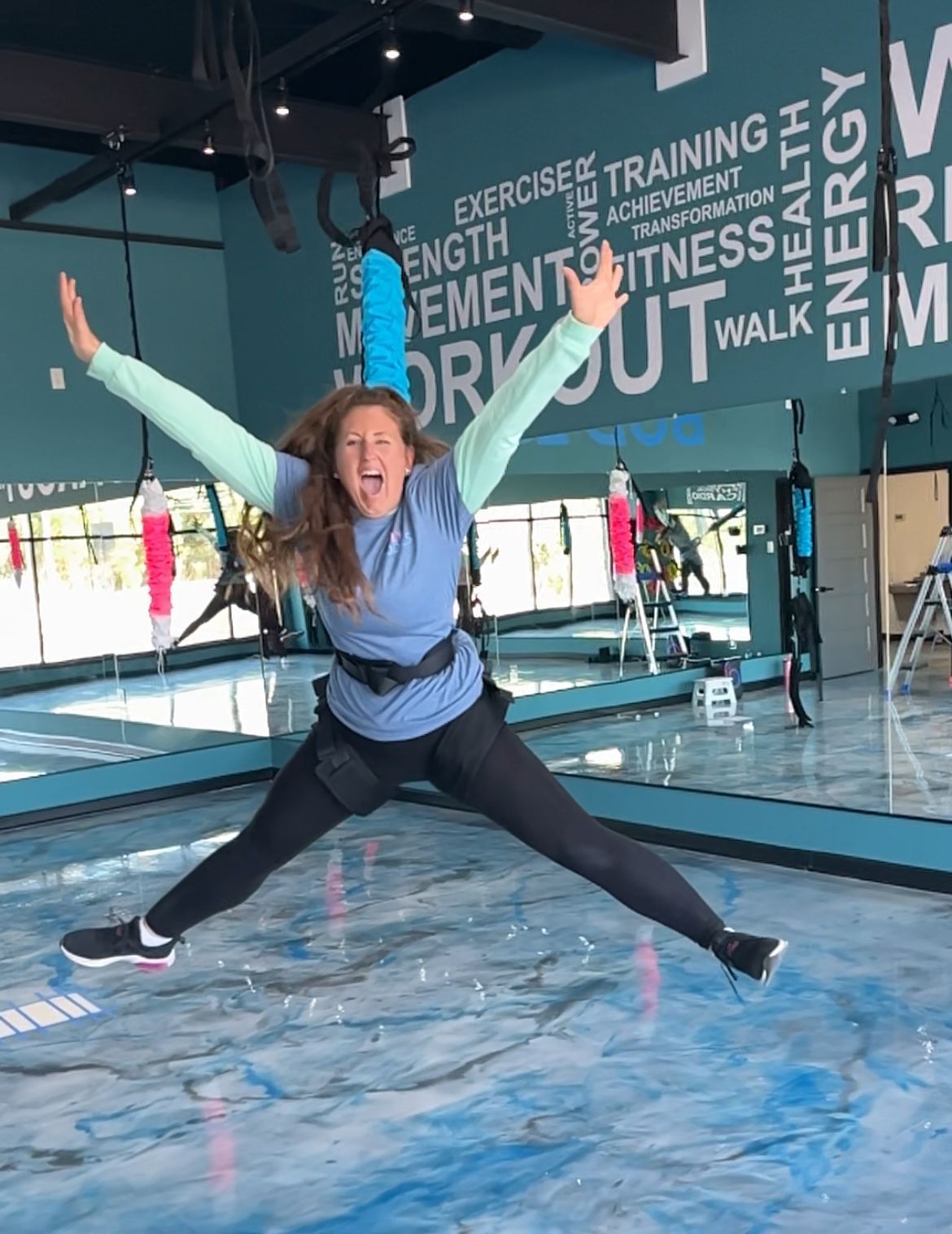 A woman is jumping in the air in a gym.