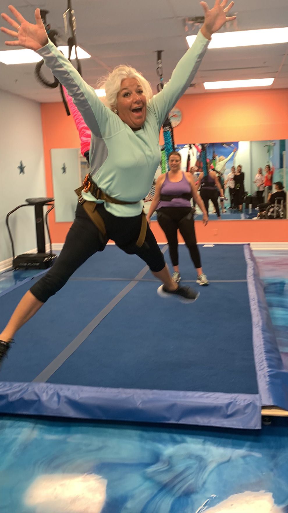 A woman is jumping in the air on a trampoline in a gym.