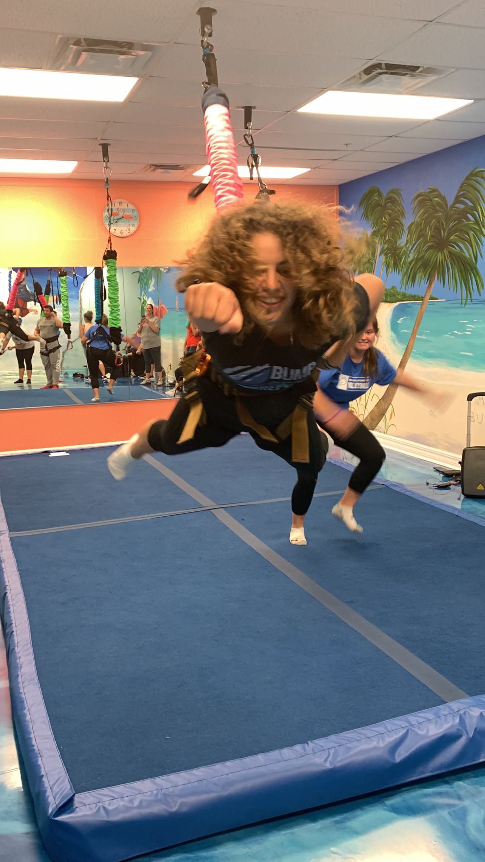 A woman is flying through the air on a rope in a gym.