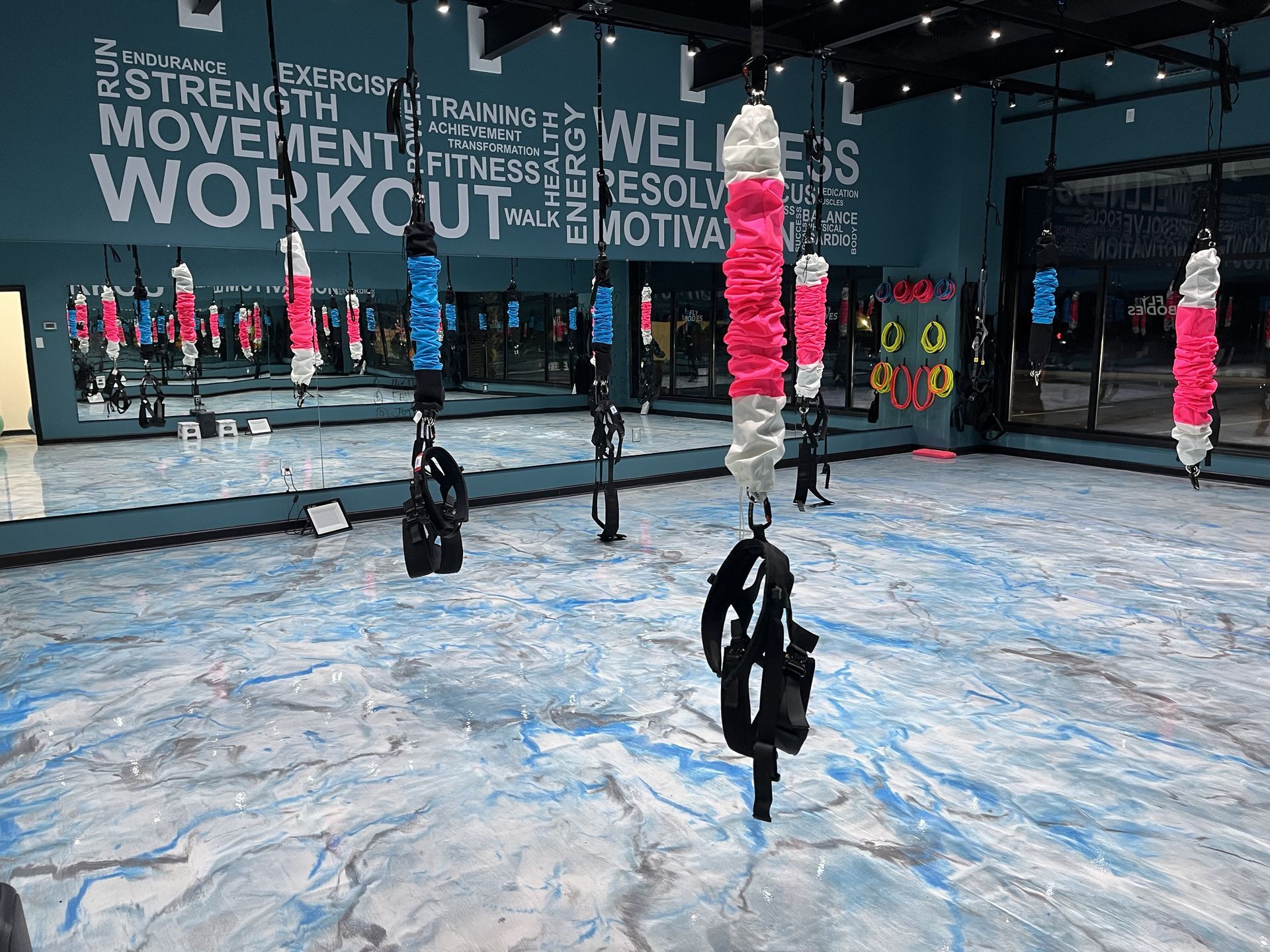 A gym with a lot of mirrors and exercise equipment hanging from the ceiling.