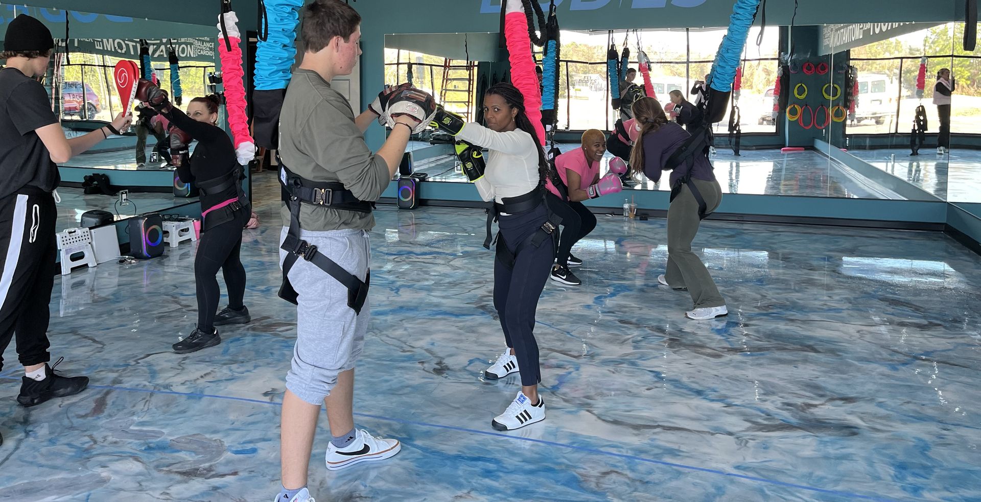 A group of people are hanging from a bungee cord in a gym.
