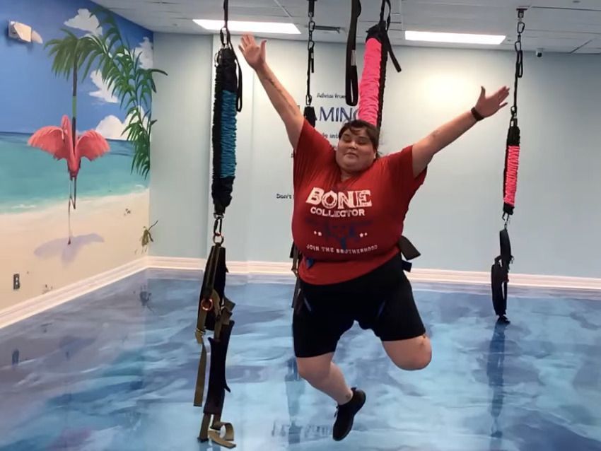 A woman wearing a red shirt that says bone on it is jumping in the air