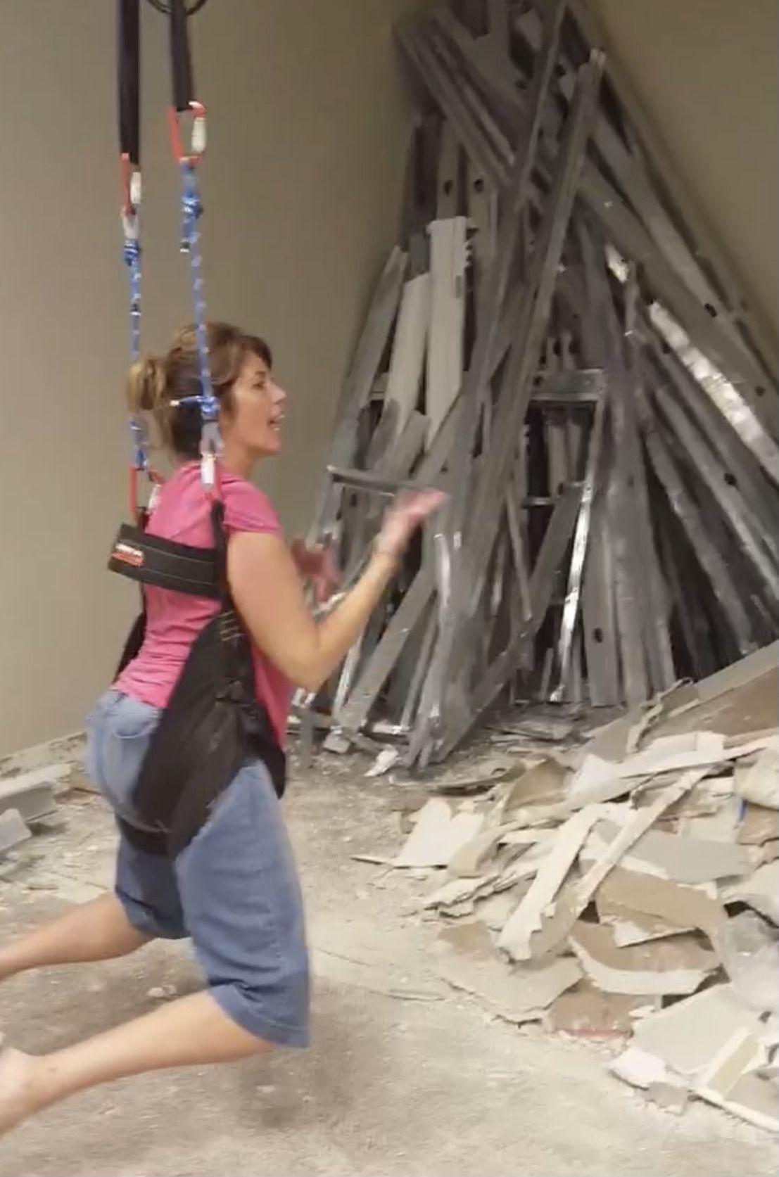 A woman in a pink shirt is kneeling down in front of a pile of cardboard