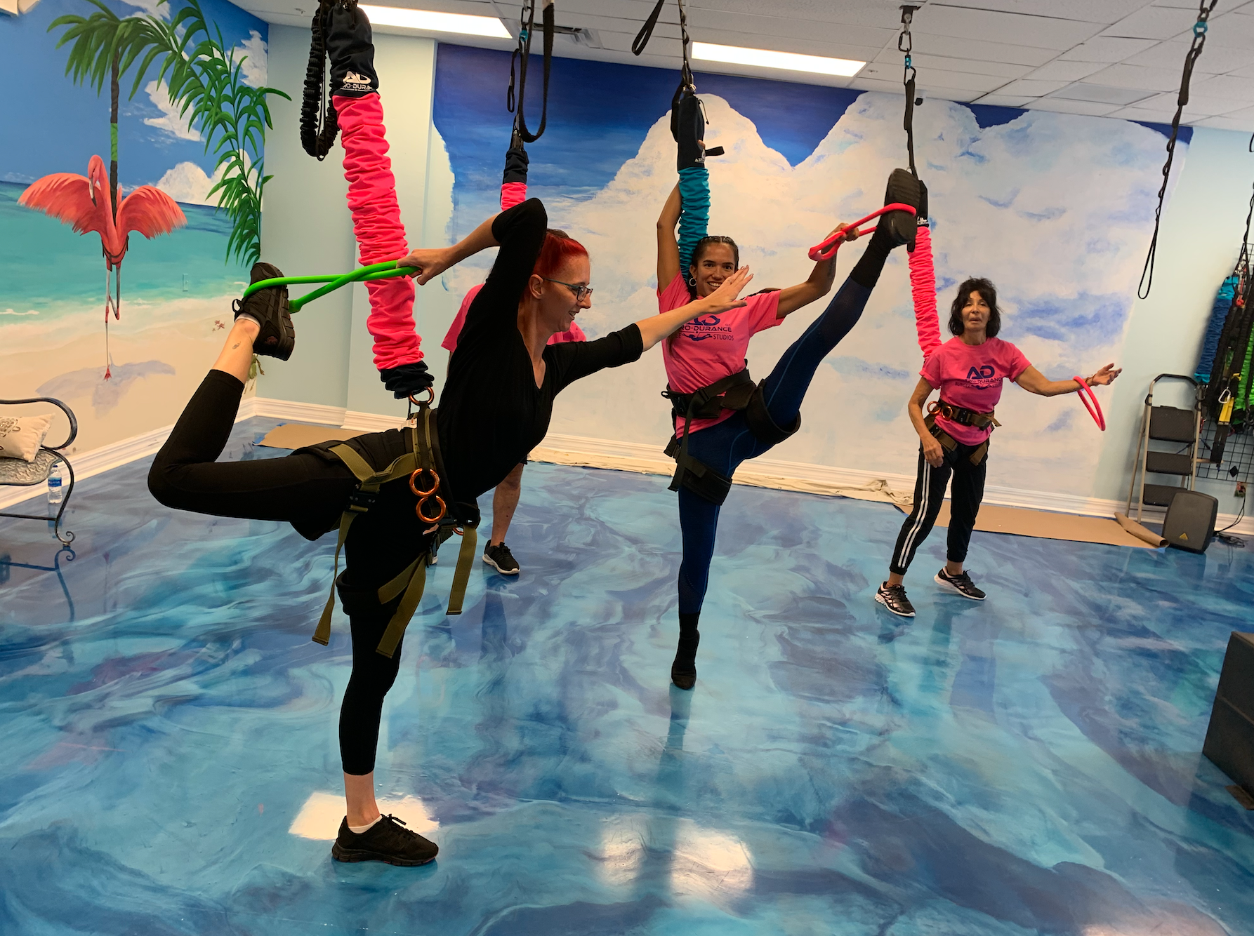 A group of people are doing aerial yoga in a gym.