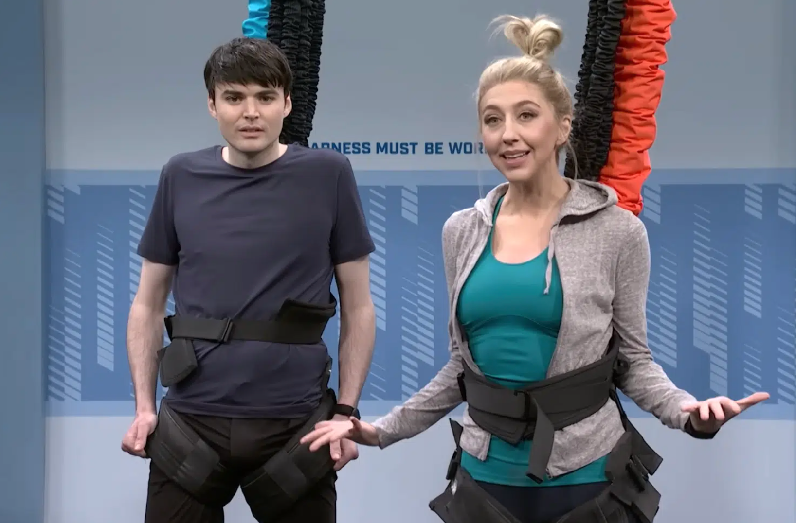 A man and a woman are standing next to each other in a gym.