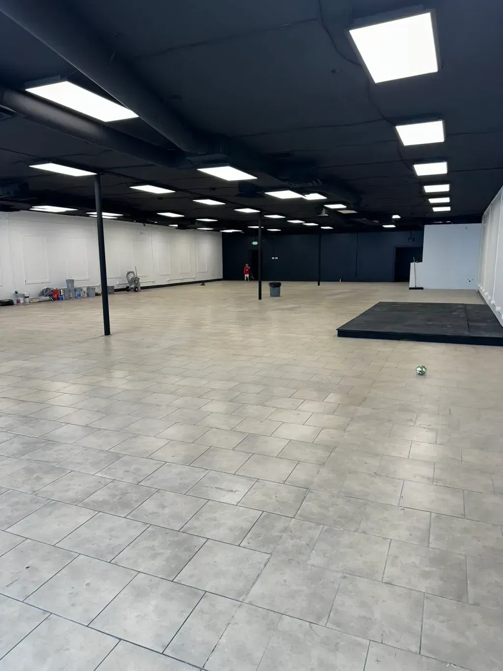 Empty commercial space with gray flooring, black ceiling, and white walls.