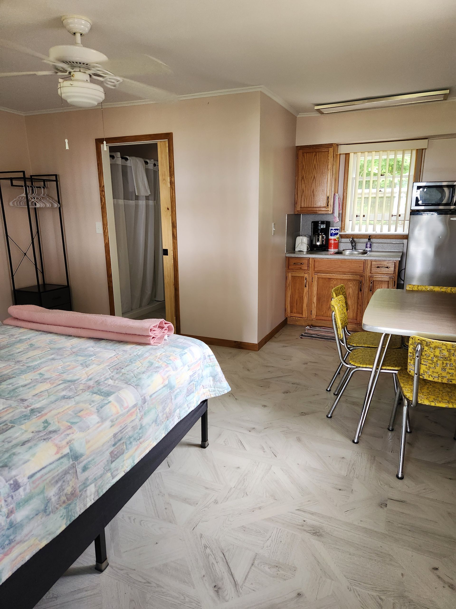A small, sparsely furnished room with a bed, small kitchenette, and dining table.