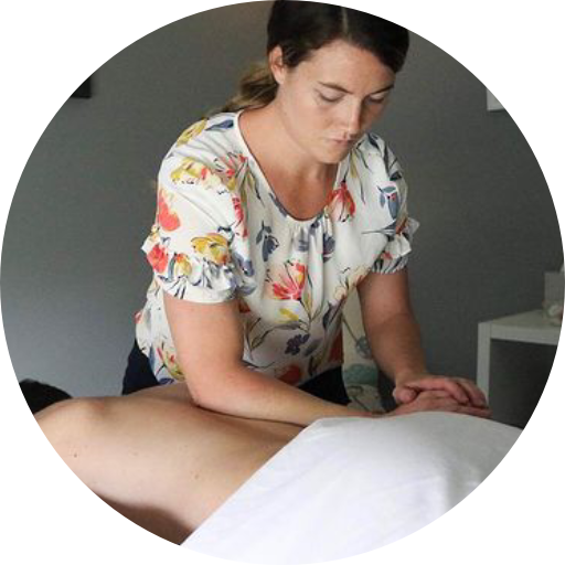 A woman is giving a massage to a person laying on a bed.
