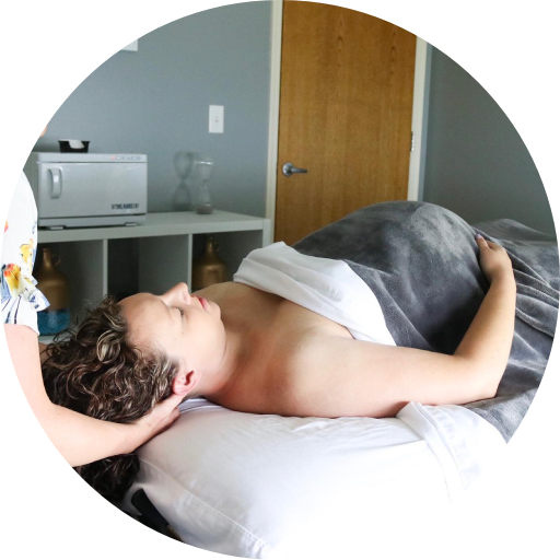 A pregnanat woman is laying on a bed getting a massage