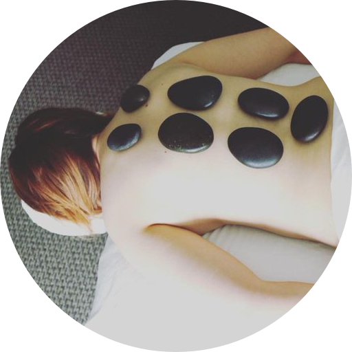 A woman is getting a massage with hot stones on her back