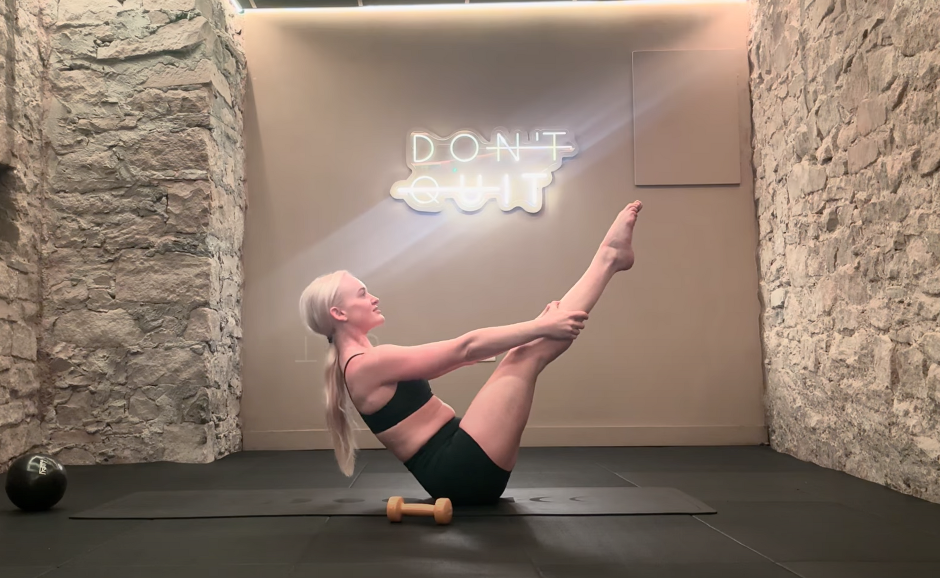 Woman doing a Pilates exercise on a mat in front of a