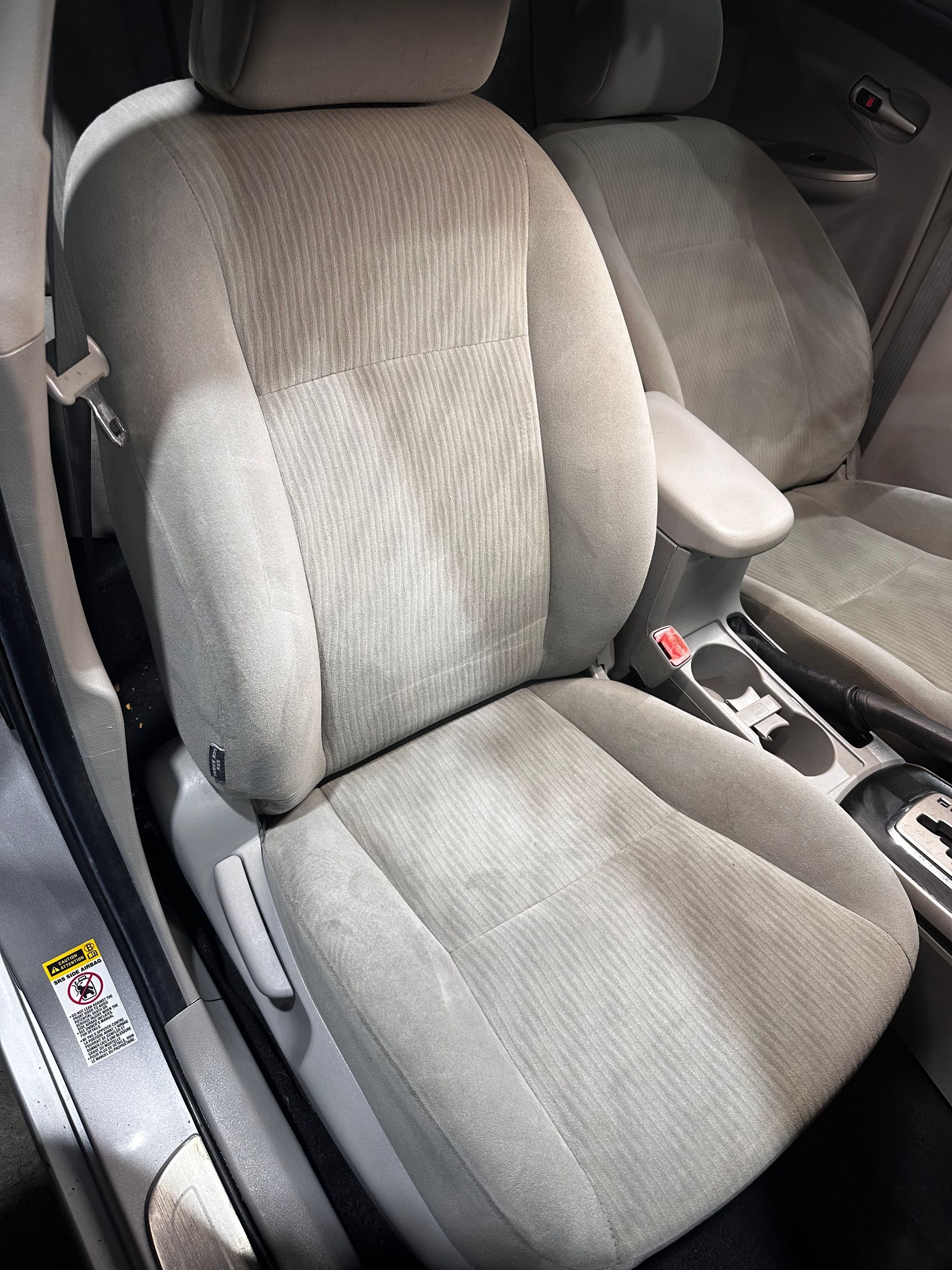 Close-up of beige fabric front car seats and center console with cup holders.