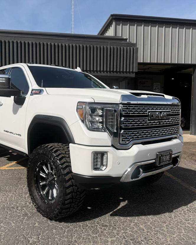 Three tires with silver, five-spoke alloy wheels leaning against a wall in a garage.