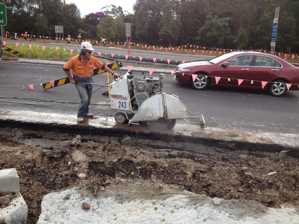 Worker Grind Hard Asphalt Road — Concrete Cutters In Port Macquarie, NSW