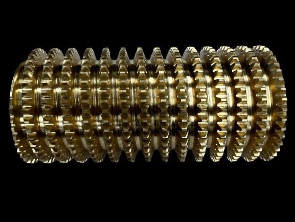 Gold-colored, cylindrical gear assembly against a black background. Many stacked gears make up the larger cylinder.