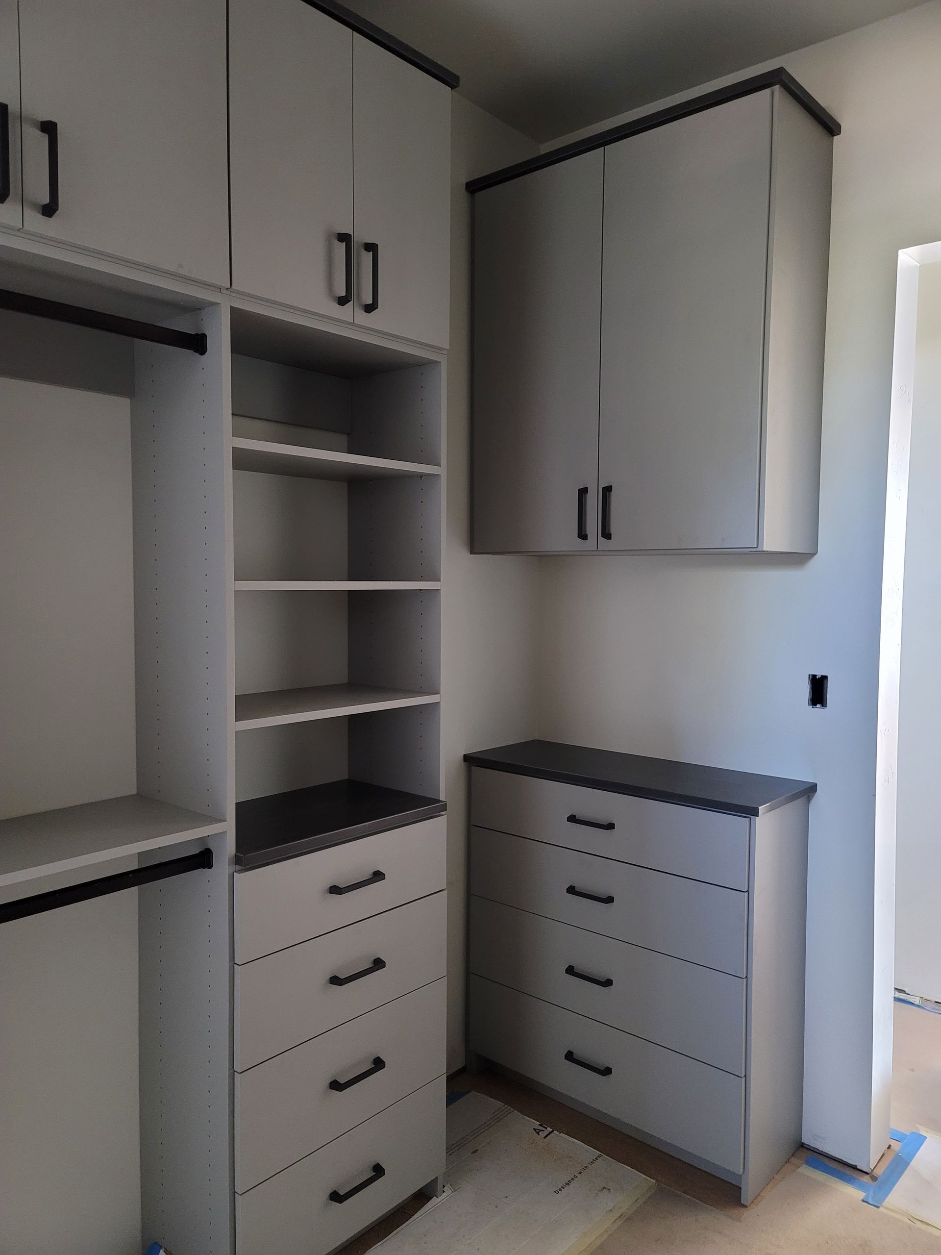 Built-in white closet with shelves and drawers in a bright room, near a window.