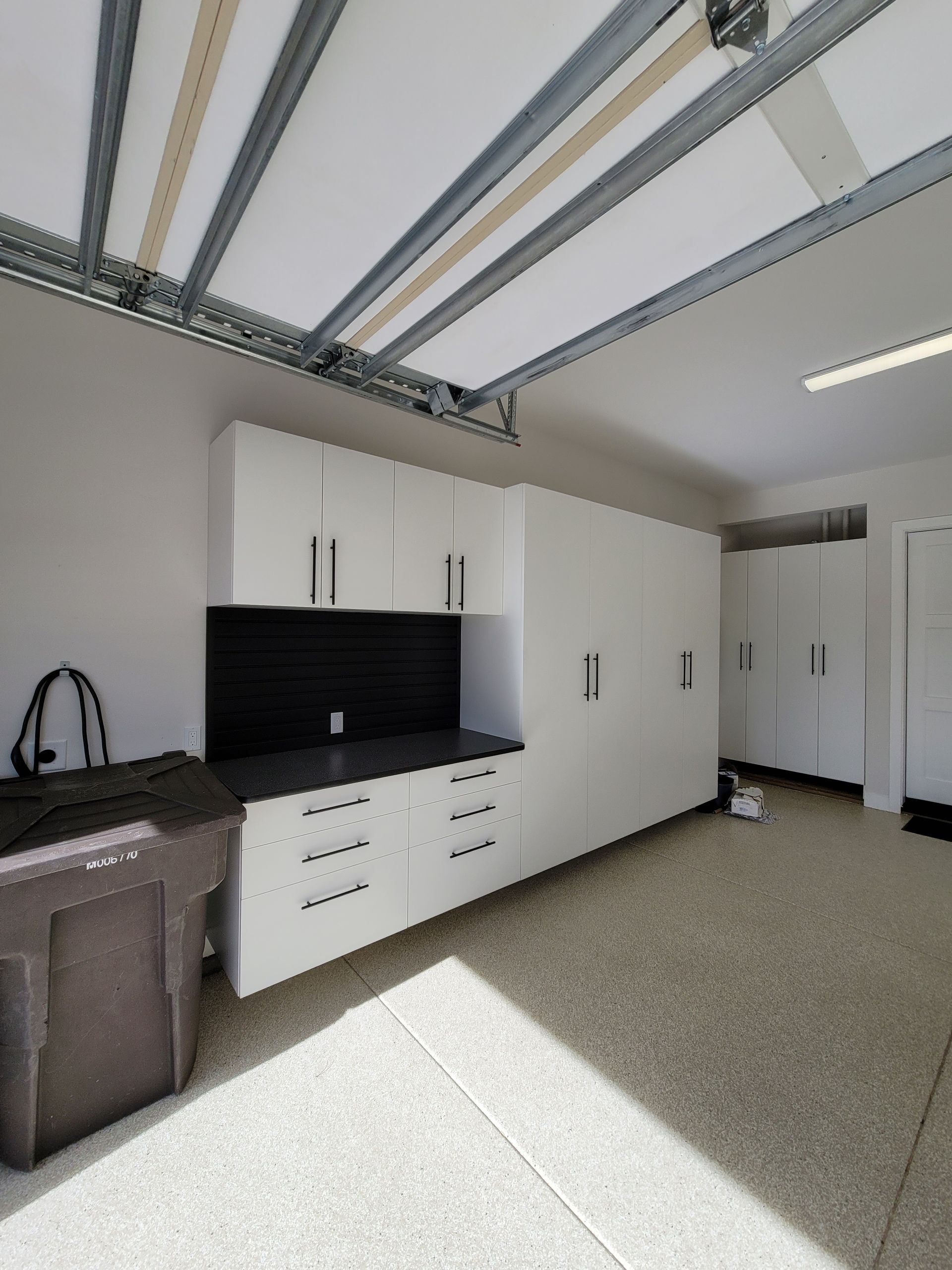Garage with white storage cabinets, black countertop, and beige floor, viewed from inside.