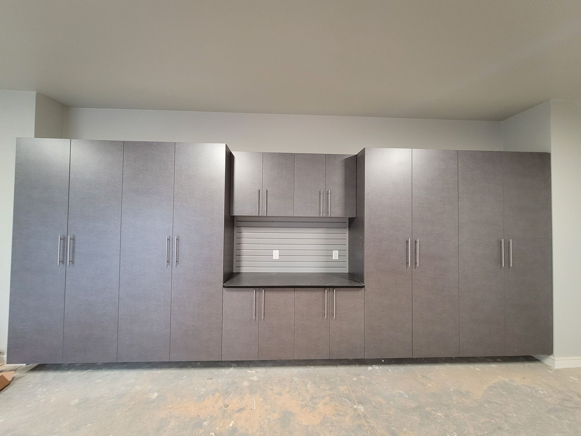 Wall of gray kitchen cabinets with a stainless steel sink centered in the middle.
