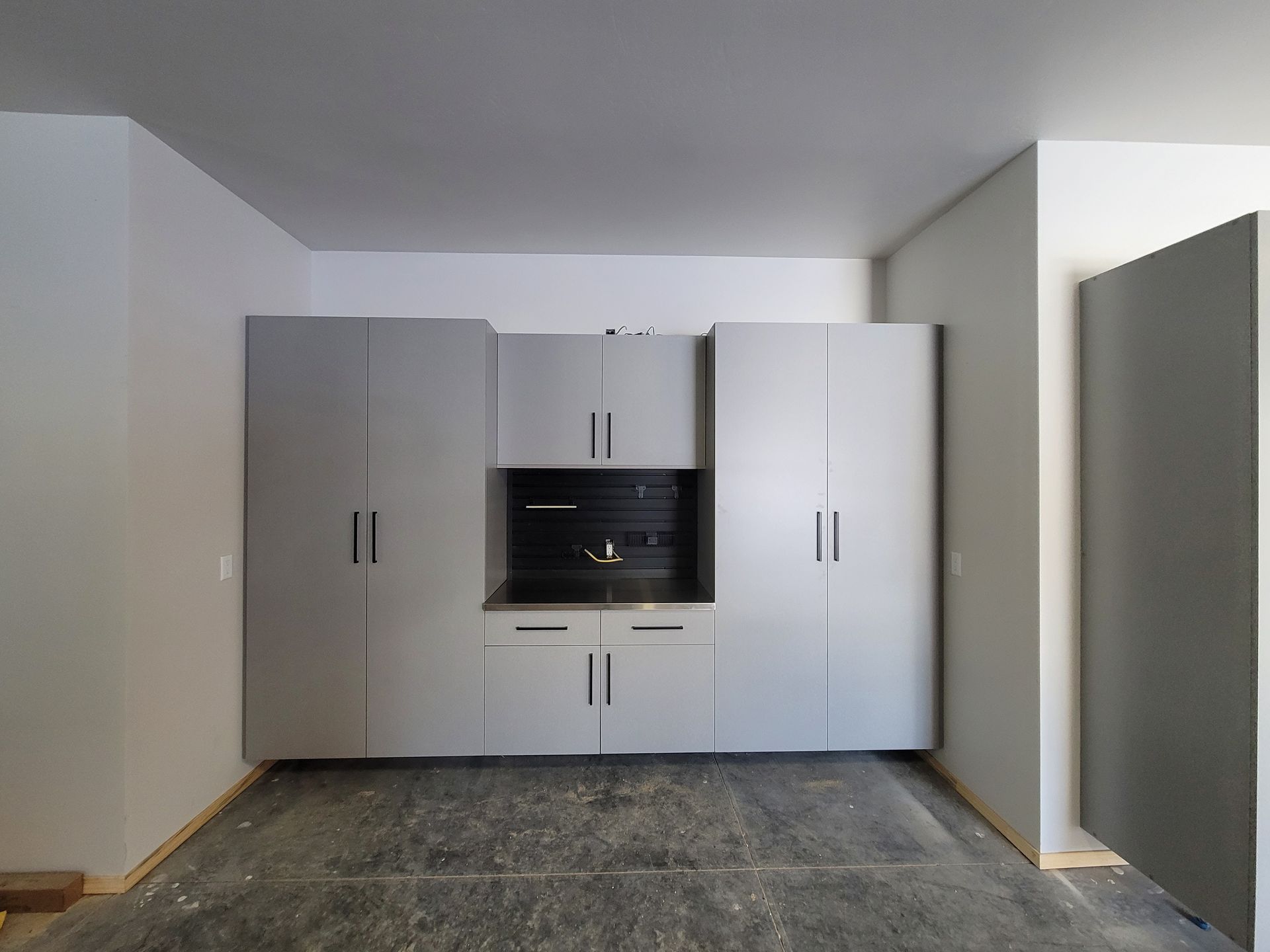 Empty room with white cabinets, built-in oven, and gray flooring.