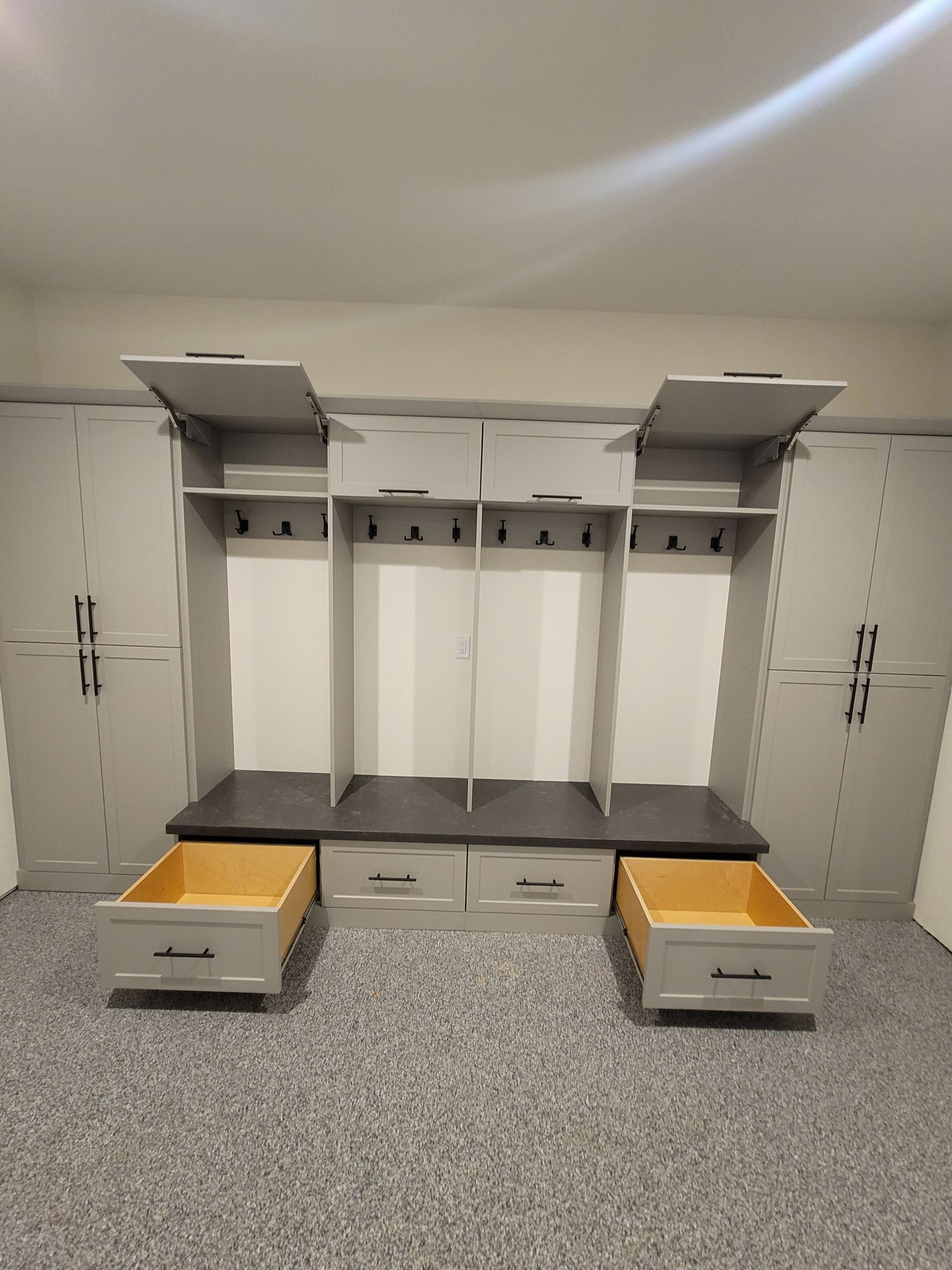 White built-in closet with open shelves, hanging rods, and two yellow bench drawers on a speckled gray floor.