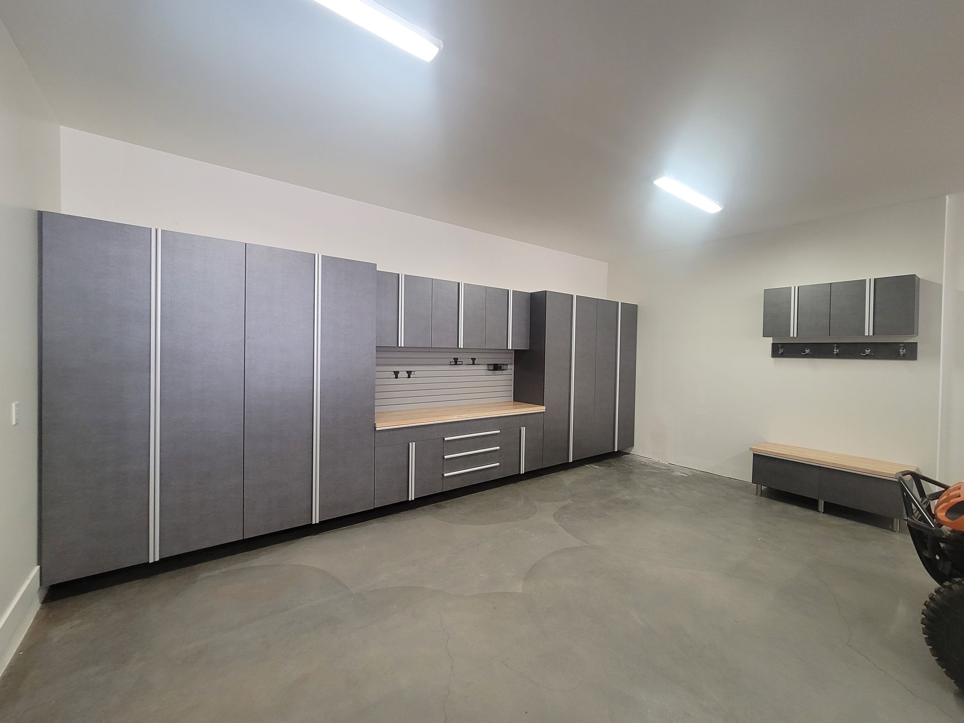 Spacious garage with gray storage cabinets, workbench, and concrete floor under bright ceiling lights
